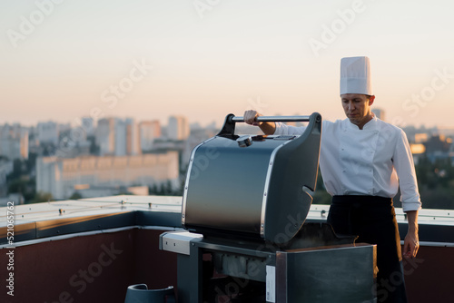 Skyscraper Rooftop: professional chef prepares a barbecue at a party or outdoor restaurant. Grilled meat, vegetables