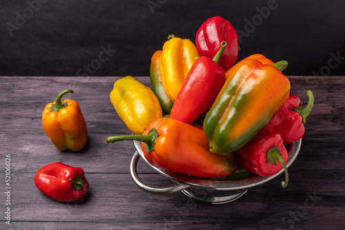 Colorful sweet peppers in a colander on a wooden table view from above