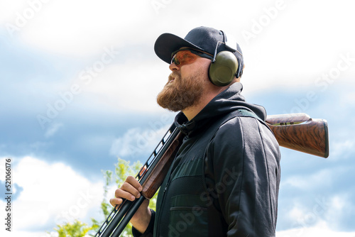 Tableau sur toile Portrait of a 30-35-year-old male shooter with a sports rifle on his shoulder, w