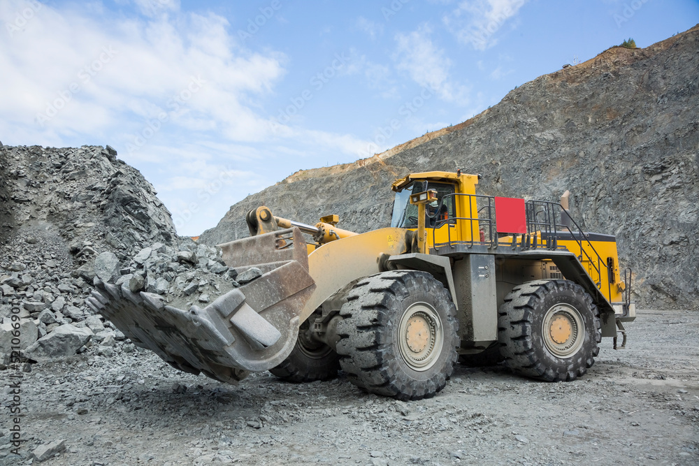 Quarry for iron ore extraction. Mining of copper ore. Transportation of copper ore rocks by dump trucks. Large quarry yellow truck, equipment for working with copper ore rocks. Mining works.
