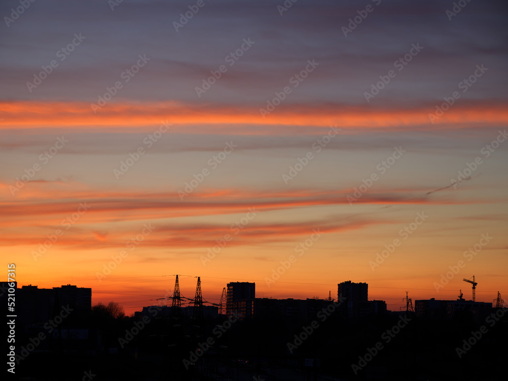 Bright sunset sky over the silhouette of the evening city.