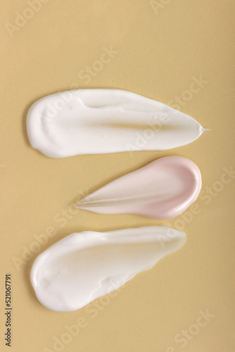 Texture of smears of cream and serum on a pink background. Cosmetics smeared on the table.