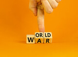 World war symbol. Concept words World war on wooden cubes. Businessman hand. Beautiful orange table orange background. Business and World war concept. Copy space.