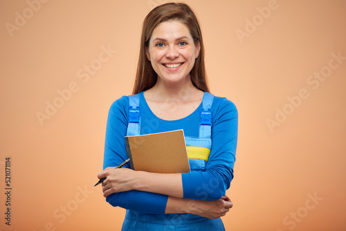 woman student in blue overalls holding workbook. Isolated female portrait.