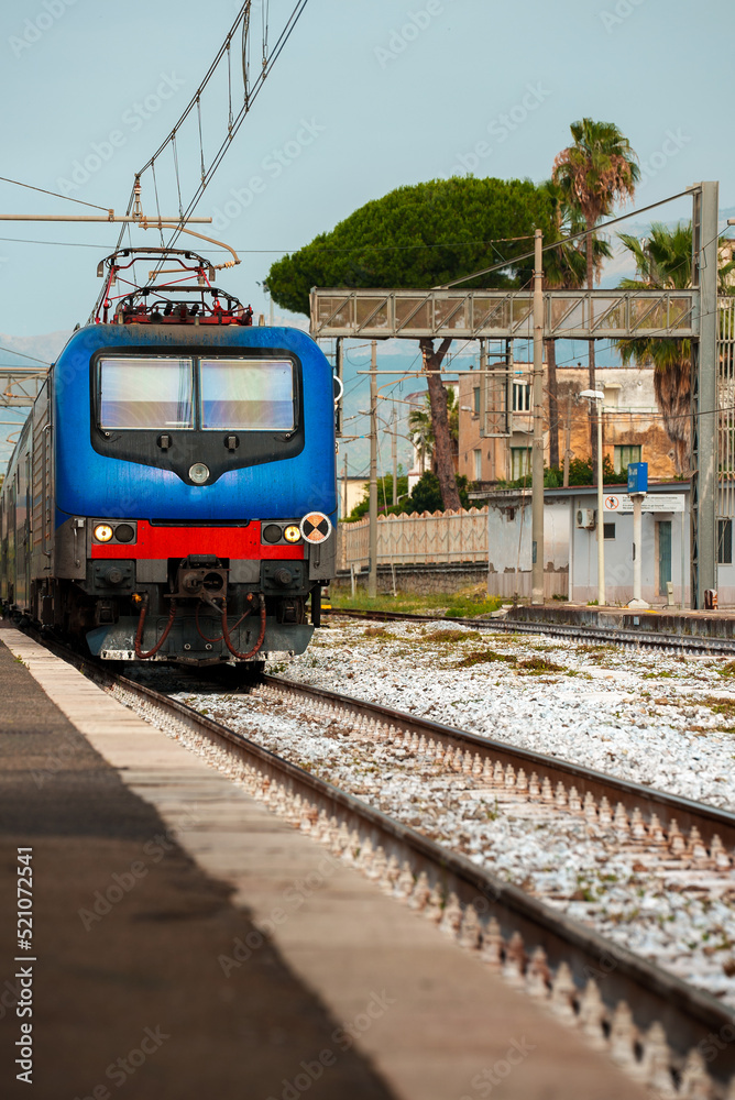 Naklejka premium Train arrives at regular rural train station in Italy.