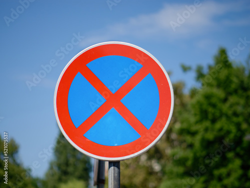 Close-up photo of no parking and no stopping traffic sign with the sky and trees in the background