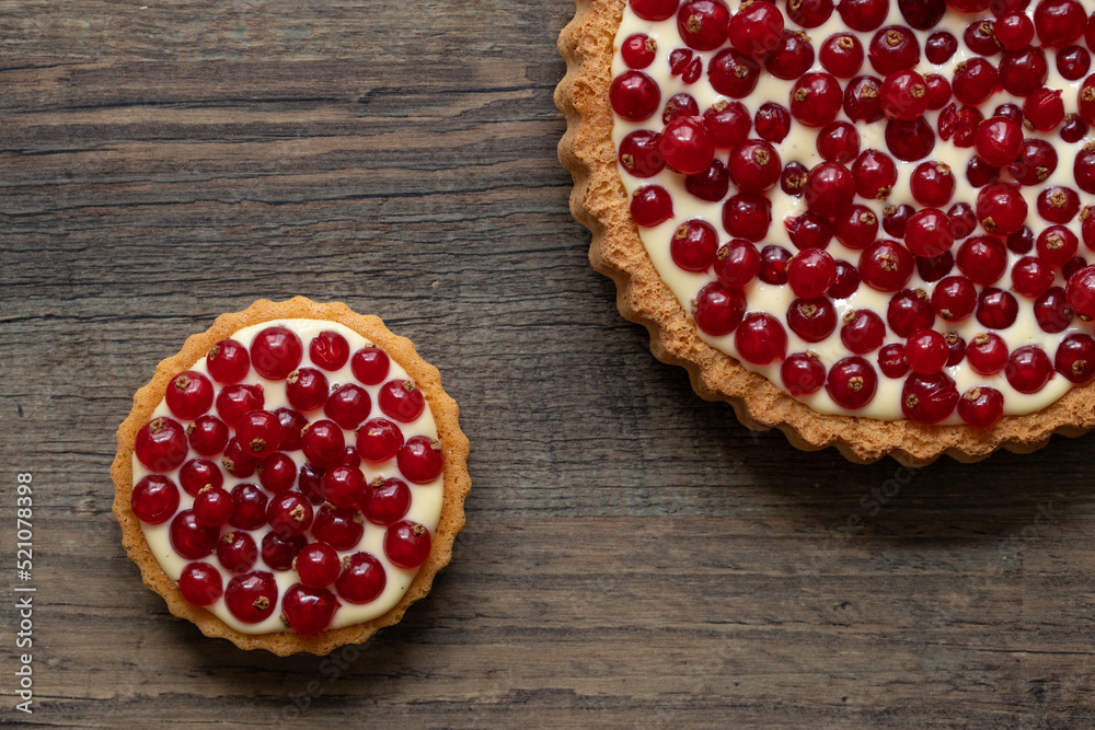 rote Johannisbeeren und Pudding in Törtchen auf Tisch aus Holz rote Johannisbeeren und Pudding in Törtchen auf Tisch aus Holz
