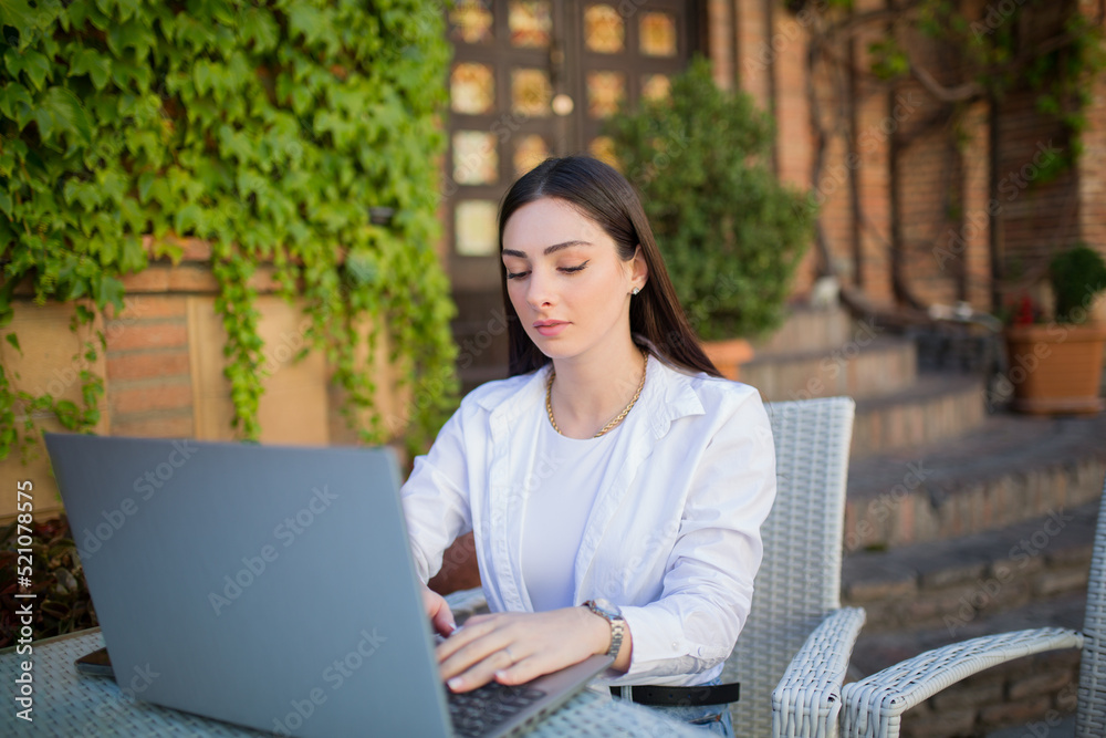 Young woman working on a computer outdoors. Freelancer in a cafe Young woman working on a computer outdoors. Freelancer in a cafe