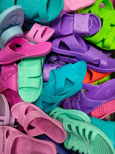 multi colored women's beach flip flops in the basket of a shoe store