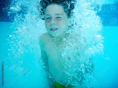 underwater photo of child diving in the pool
