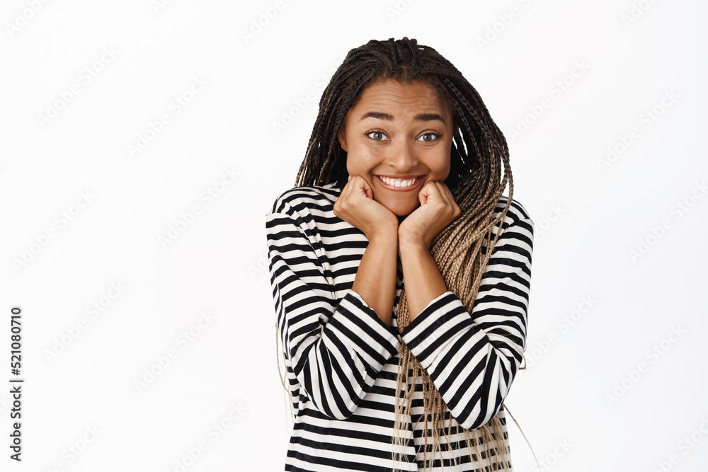 Smiling excited black girl waiting for smth with anticipation, yearning, looking with interest and amusement at camera, standing over white background Smiling excited black girl waiting for smth with anticipation, yearning, looking with interest and amusement at camera, standing over white background