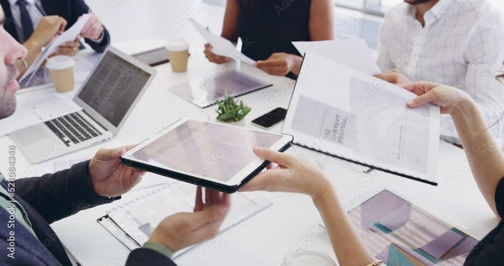Creative marketing team brainstorming together with a tablet around the boardroom table during a meeting. Professional designers working on an editorial piece for a company website or magazine page
