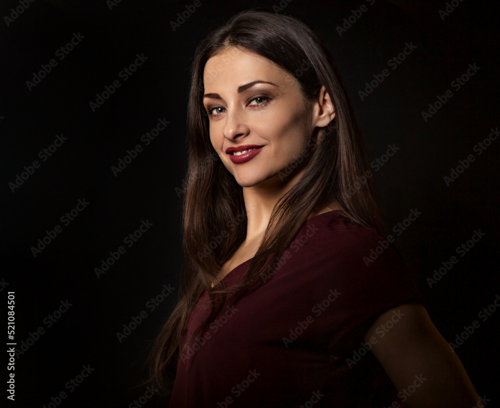 Beautiful young business toothy smiling woman thinking and looking happy in burgundy blouse and with red lipstick on dark shadow black background with empty copy space. Portrait Beautiful young business toothy smiling woman thinking and looking happy in burgundy blouse and with red lipstick on dark shadow black background with empty copy space. Portrait