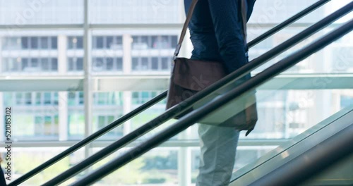 Business man traveling, talking on a phone and standing on an escalator with colleagues or coworkers. Corporate men and women working in the city and taking a break while busy in a modern office
