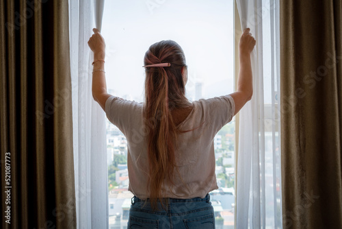 Mujer abriendo la ventana de su habitación para que entre luz natural