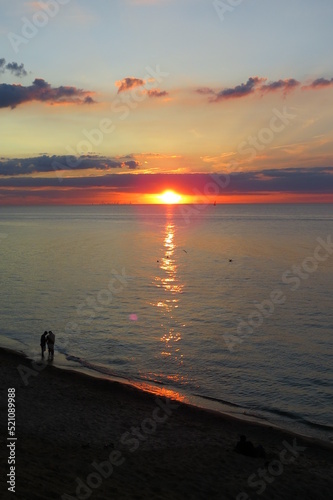sunset over great lake with people on beach and clouds