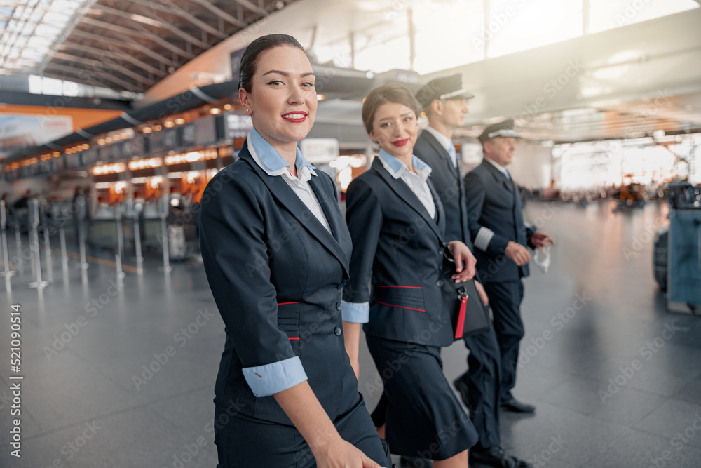 Two flight attendants and pilots walking through the terminal to the plane Two flight attendants and pilots walking through the terminal to the plane