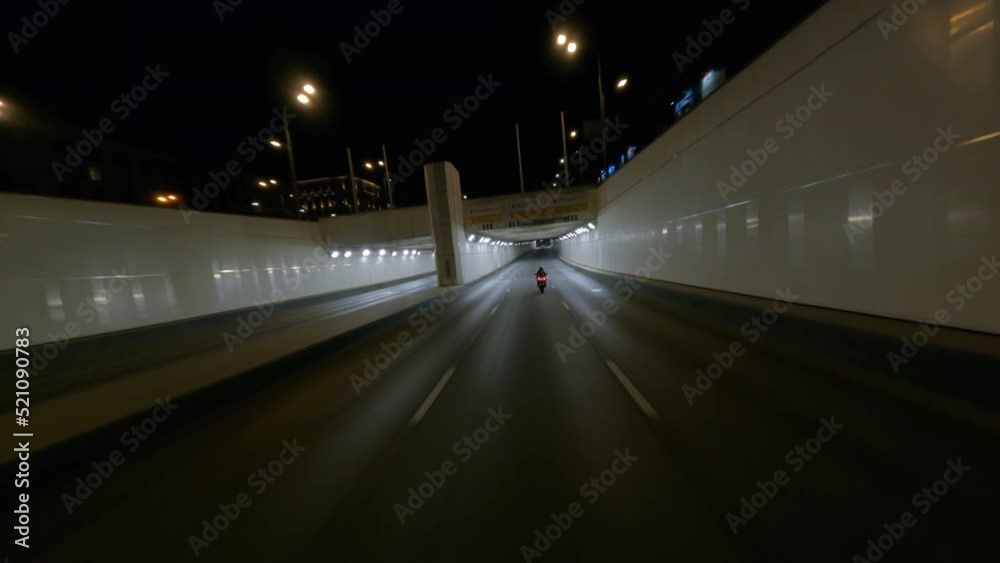 Fast BMW motorcycle rides through city tunnel in the night, fpv drone shot