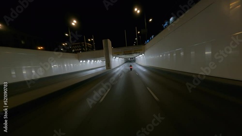 Fast BMW motorcycle rides through city tunnel in the night, fpv drone shot photo