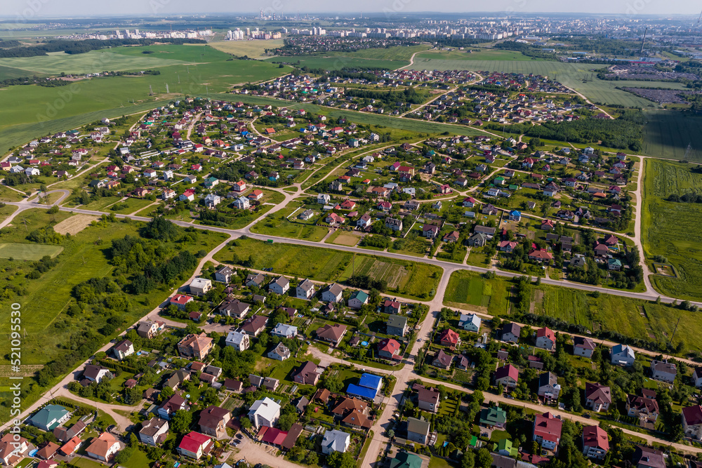 aerial panoramic view of green village with houses, barns and gravel road in forest
