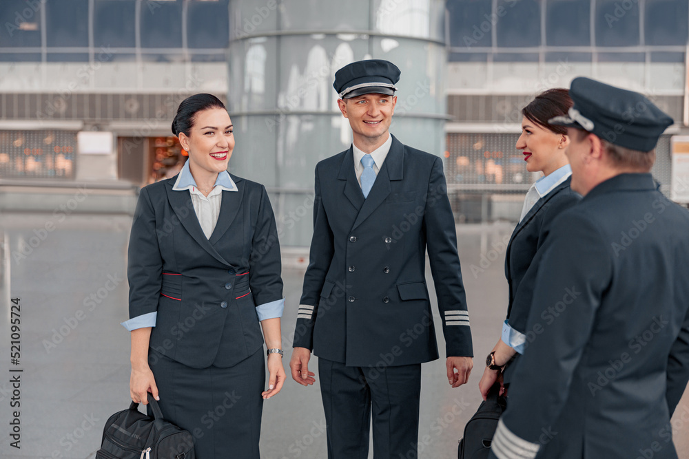 Happy pilots and stewardesses communicating in the airport terminal Happy pilots and stewardesses communicating in the airport terminal