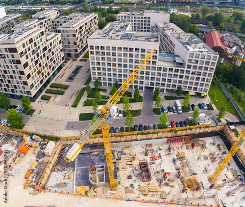 Square aerial drone perspective of construction site in the centre of Warsaw. Two yellow cranes working on a new building. High quality photo