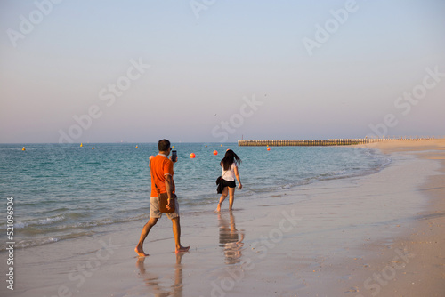 Photography Young man takes picture of his girlfriend at the beach in Dubai