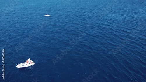 Two small white private boats on a dark-blue waters of a calm sea. Aerial view. No sky, just the sea. High quality photo