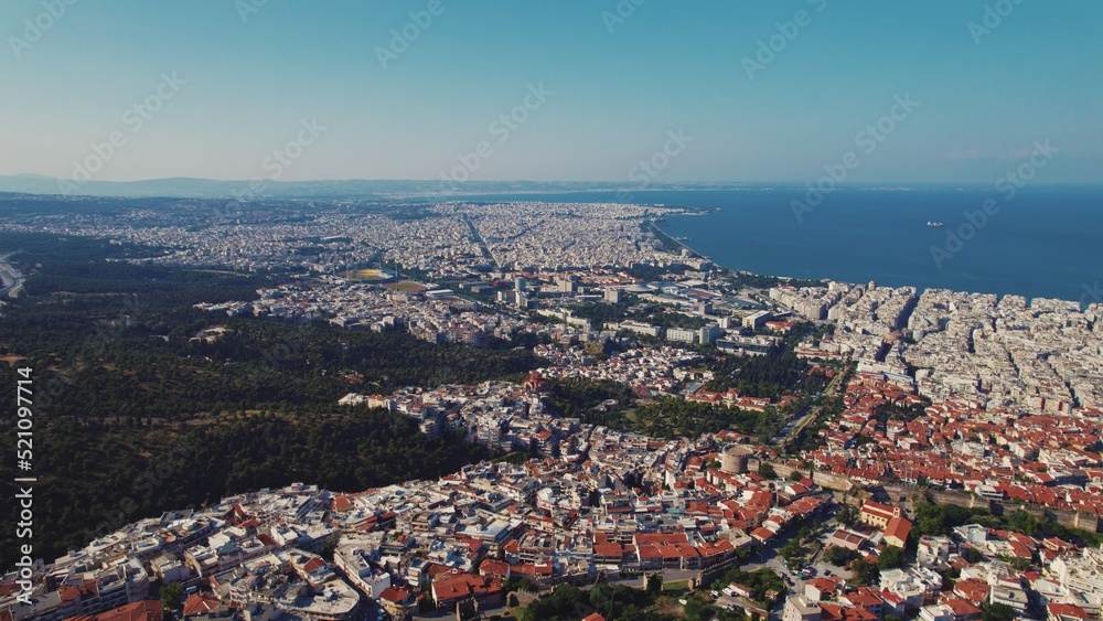 Fototapeta premium Greek city seen from aerial drone perspective. Typical Greek orange rooftops and whitewashed walls. Seashore. High quality photo
