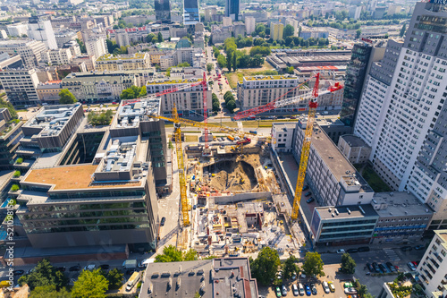 Eclectic architecture concept. Construction of a skyscraper or block of flats. Three professional cranes and construction workers doing their job. Aerial view. . High quality photo