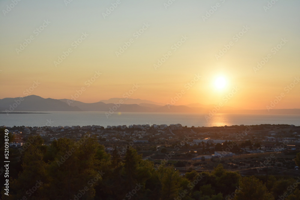 Sunset colors in the sky and reflected on the sea, with the sun and mountains at a distance. Euboea (Evia), Greece
