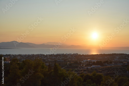 Sunset colors in the sky and reflected on the sea, with the sun and mountains at a distance. Euboea (Evia), Greece © Alexandros 