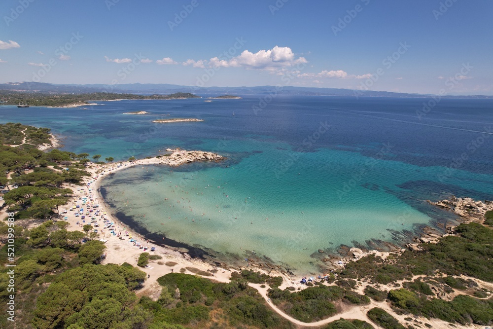 Gorgeous photogenic Karydi beach in Greece. Amazing color of water - turquoise and dark blue - white sand and relaxing tourists. High quality photo