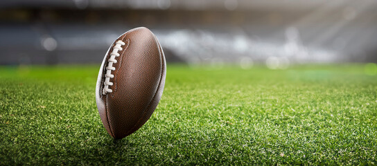 American football ball on the grass of a stadium - copyspace