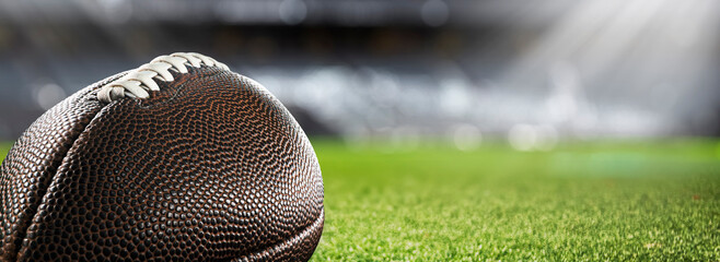 American football ball on the grass of a stadium - copyspace