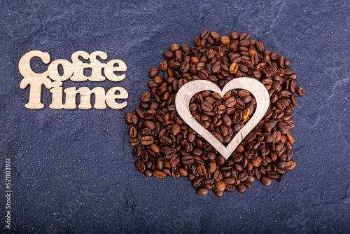 Texture background of coffee beans for design with the inscription coffee time. Coffee grains scattered on the table
