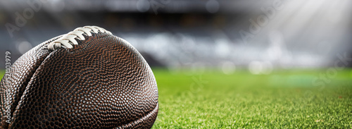 Obraz na plátně American football ball on the grass of a stadium - copyspace