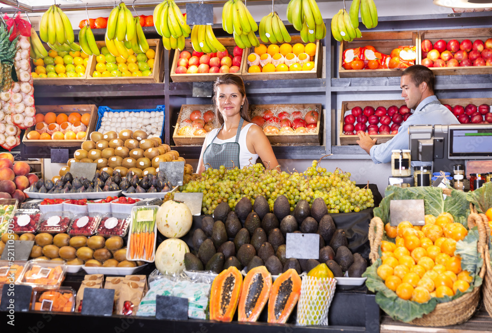 Young woman selling fresh grapes and fruits at a supermarket