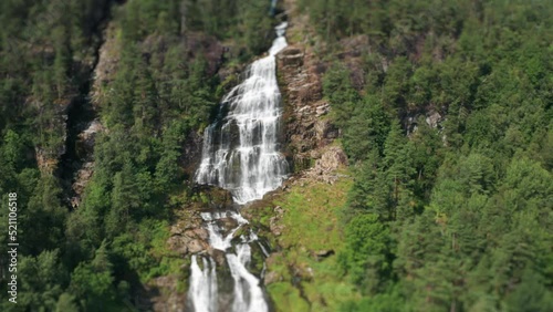 A tilt-shift video of the Svandalsfossen waterfall. Revealing shot. Slow-motion. Pan backward. photo
