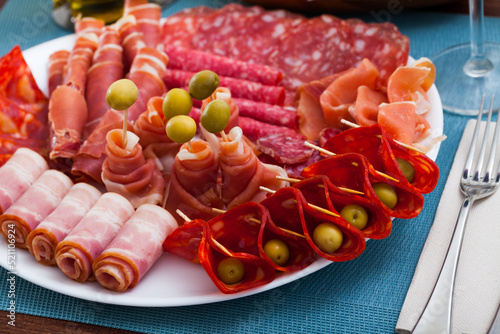 Appetizer of various types of Spanish sausages on platter served to wine
