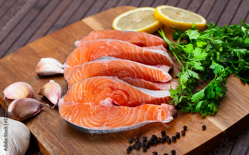 Fresh sliced salmon on wooden cutting board with lieces of lemon and parlsey sprigs.