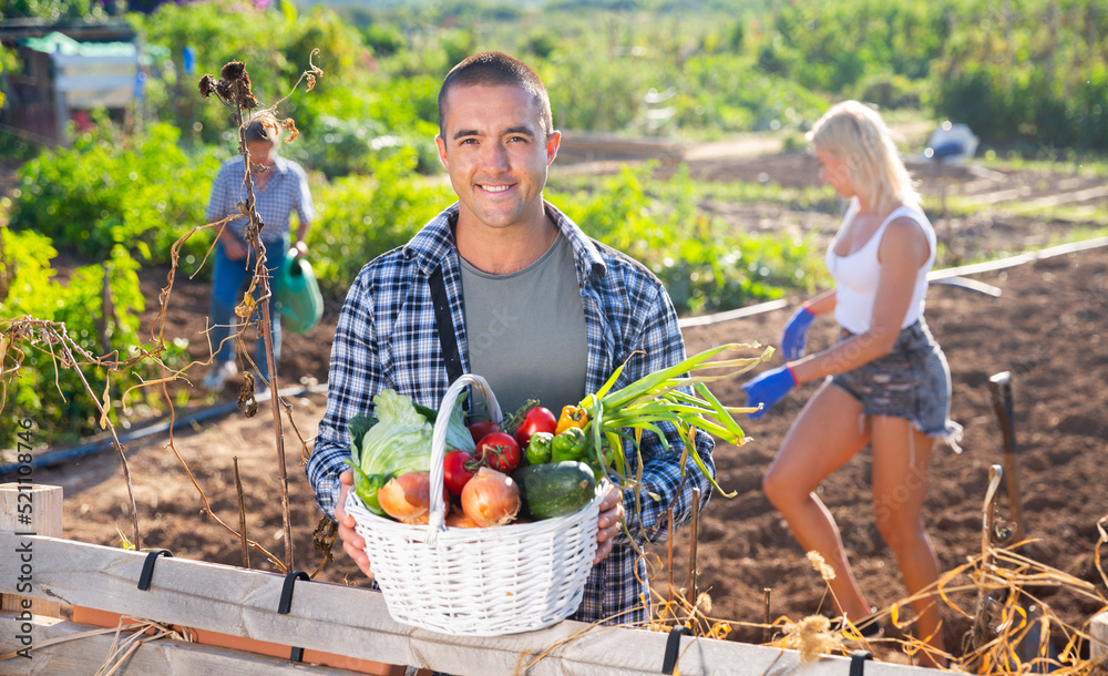 Fototapeta premium Happy farmer with basket of vegetables in the garden
