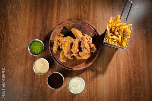 the photograph shows some delicious chicken wings accompanied by potatoes, beer