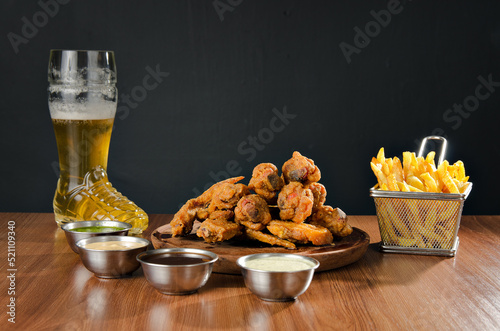 the photograph shows some delicious chicken wings accompanied by potatoes, beer