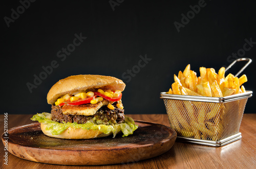 the photograph shows a delicious hamburger accompanied by french fries