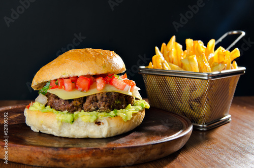 the photograph shows a delicious hamburger accompanied by french fries