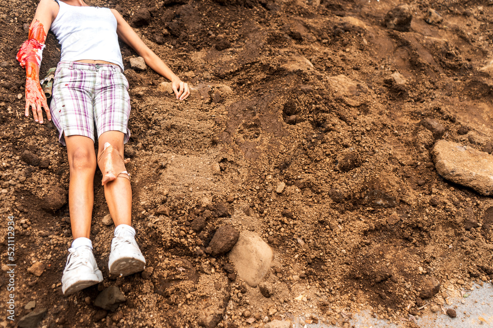 Fototapeta premium Horizontal photo of an unrecognizable young Latin woman victim of femicide lying on a pile of dirt