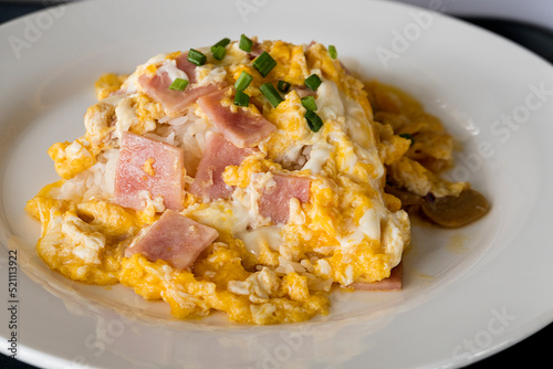 Scrambled egg and ham with rice on white dish.