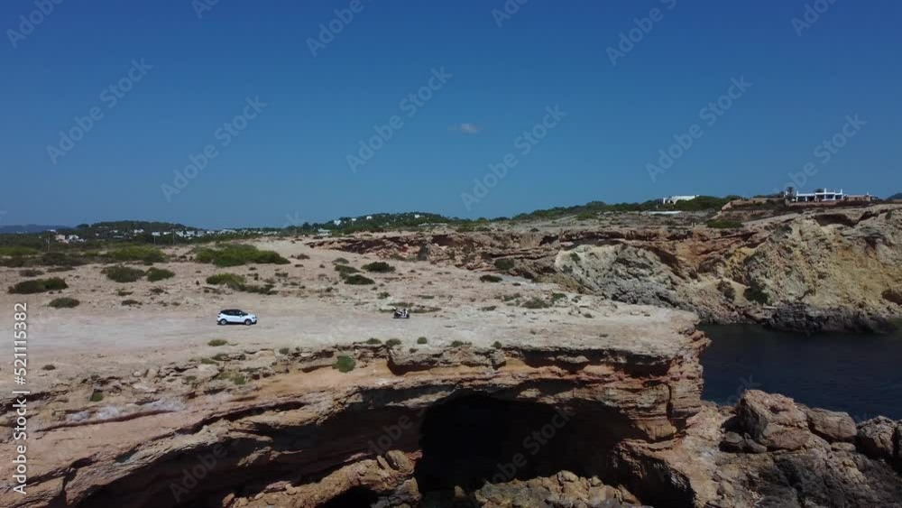 A single white car and a scooter Parking on rock
Smooth aerial view flight pedestal down drone footage
of cliff edge beach Sa Figuera borda Ibiza summer 2022 4k Cinematic from above by Philipp Marnitz