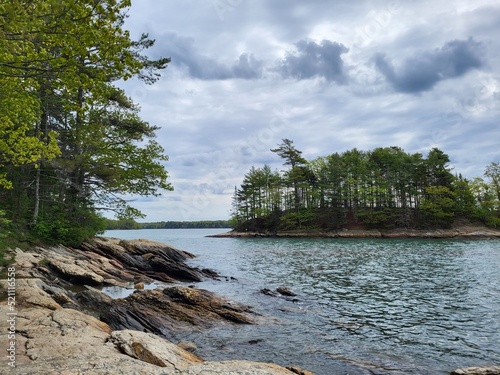 Scenic water and island with trees and clouds photo